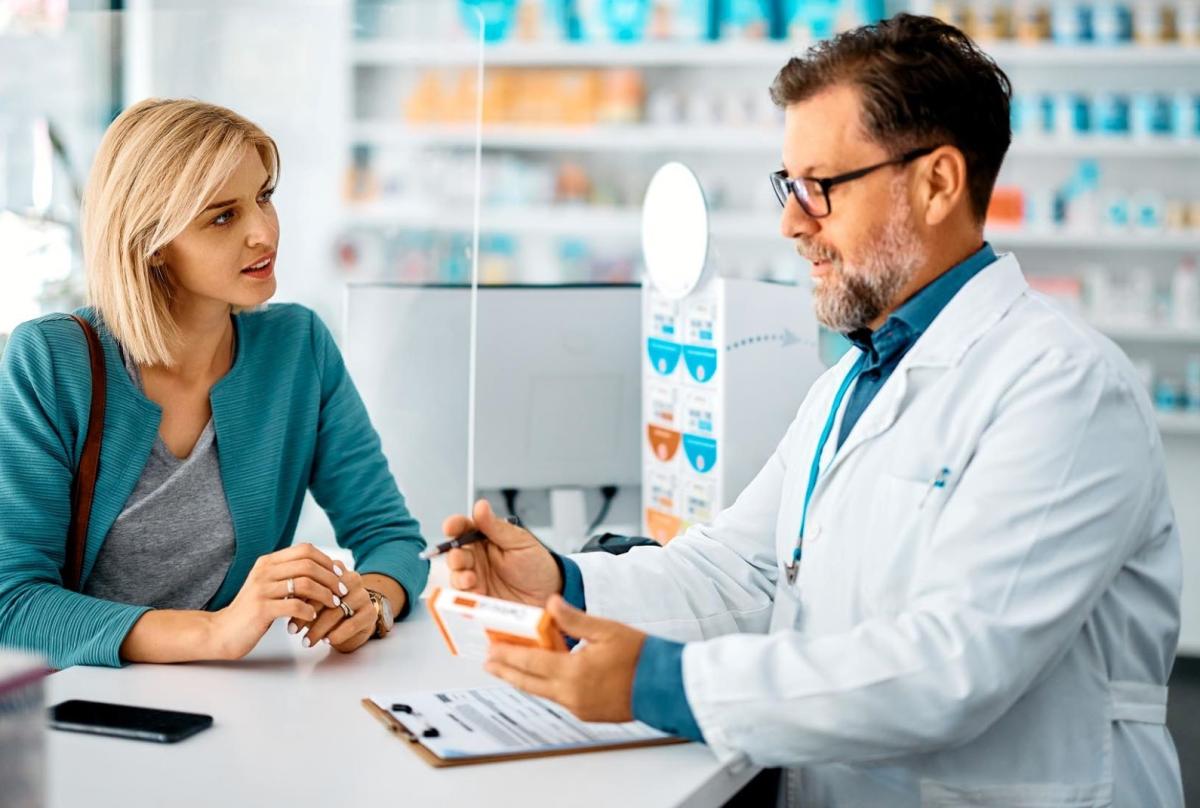 Phrarmacien remettant une boite d'antibiotiues à une patiente/Apotheker die een doos antibiotica aan een patiënt overhandigt Phrarmacien remettant une boite d'antibiotiues à une patiente/Apotheker die een doos antibiotica aan een patiënt overhandigt