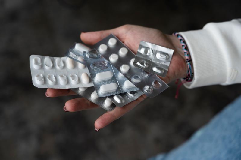 Main tenant plusieurs plaquettes de comprimés illustrant l’usage ou la surconsommation de médicaments