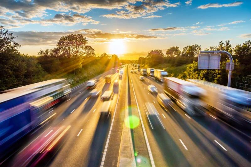 Vue dynamique d’une autoroute très fréquentée au coucher du soleil, illustrant la densité du trafic routier et les enjeux liés aux zones à faibles émissions