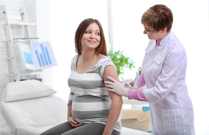 Femme enceinte en consultation avec un médecin qui écoute sa respiration / Zwangere vrouw in overleg met een arts die naar haar ademhaling luistert