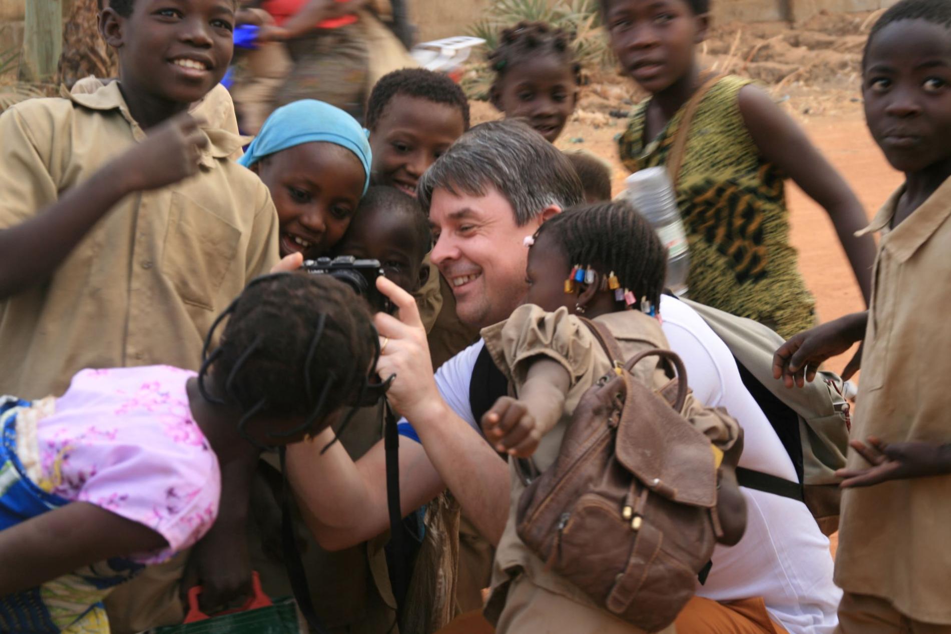 Xavier Brenez directeur des Mutualités Libres souriant réalise des photos entouré d'enfants 