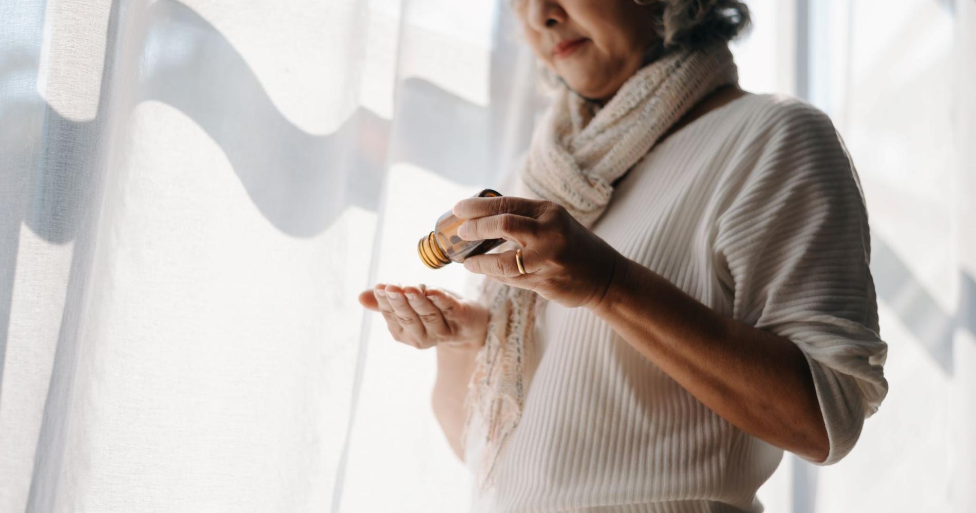 Femme versant des comprimés dans sa main à partir d’un flacon ambré, illustrant l’usage personnel d’opioïdes dans un contexte domestique